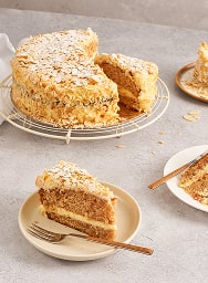 Gâteau aux amandes saupoudré de sucre glace avec une tranche servie sur une assiette avec une fourchette