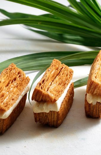 Trois petits fours aux amandes avec glaçage blanc et tiges d'oignon frais vert sur surface blanche