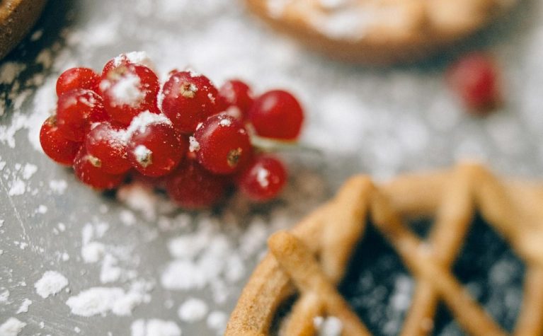 Groseilles rouges recouvertes de sucre glace avec biscuits sablés en arrière-plan
