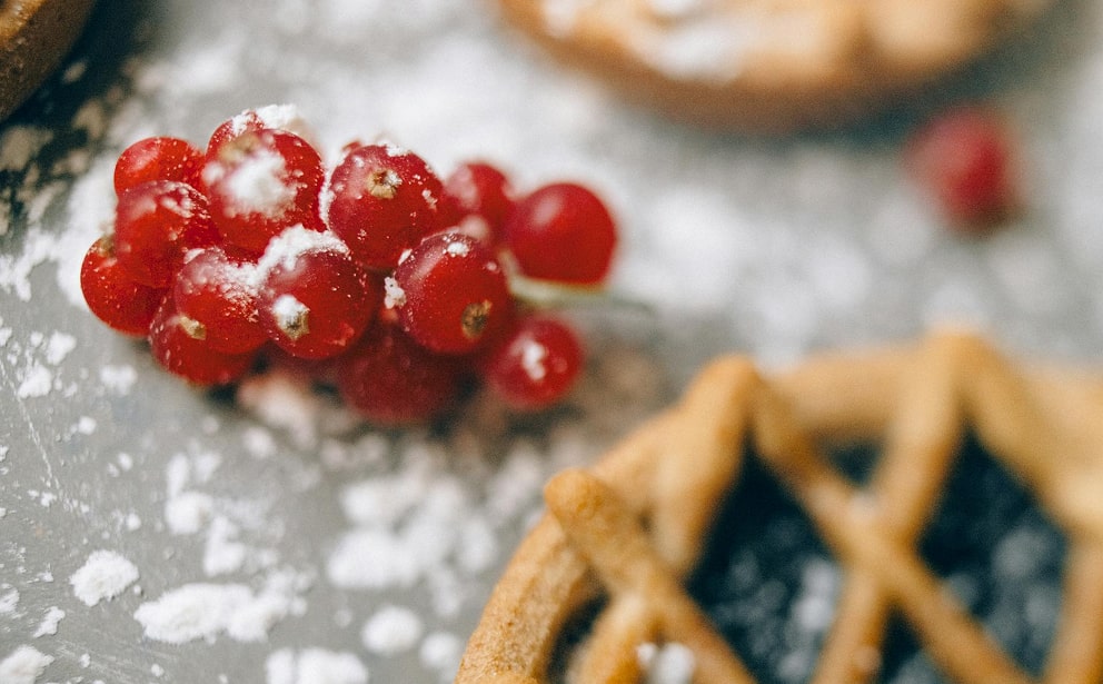 Groseilles rouges recouvertes de sucre glace avec biscuits sablés en arrière-plan