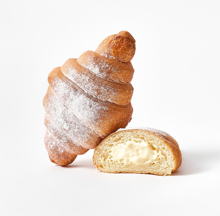 Croissant feuilleté saupoudré de sucre glace avec une moitié tranchée révélant la garniture à la crème