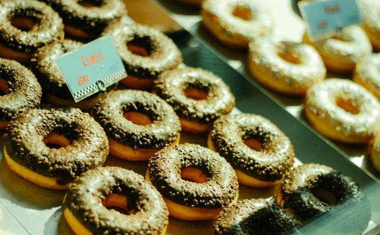 Donuts glacés au sucre cristallisé avec garniture au centre, présentés sur un plateau vert menthe avec étiquettes bleues