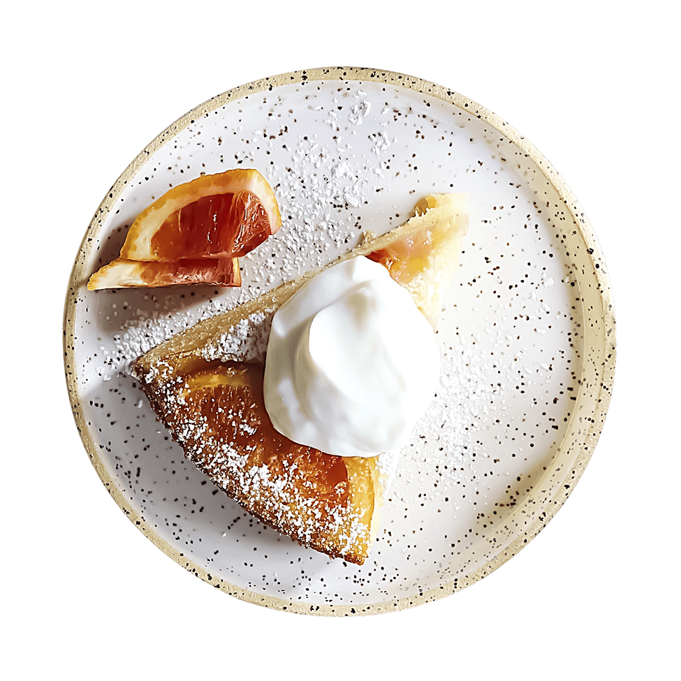 Assiette specklée avec part de gâteau au caramel, crème fraîche, grapefruit et sucre glace