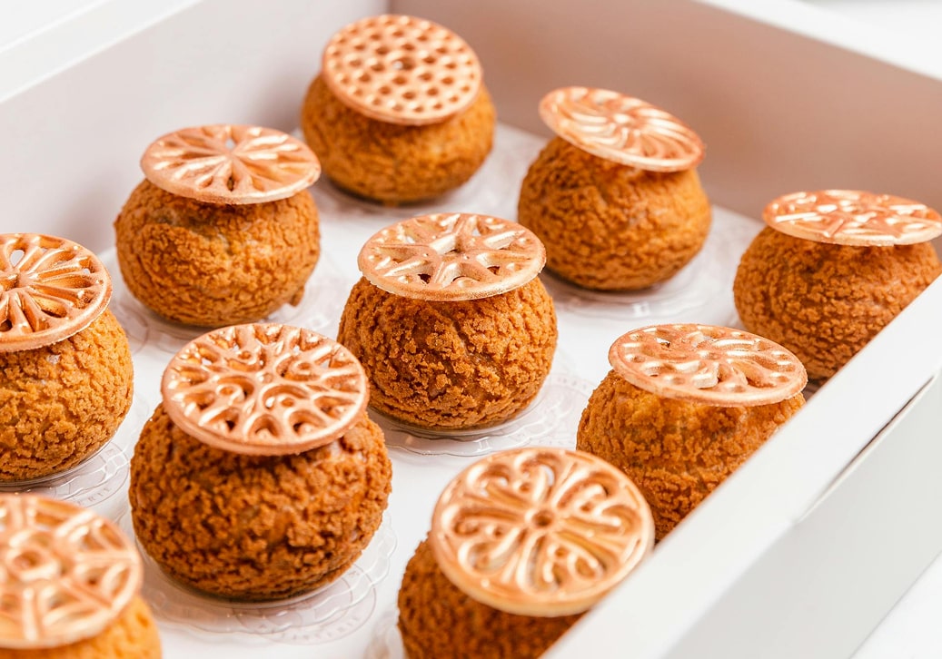 Canelés artisanaux garnis de décoration en caramel sur plateau blanc, pâtisseries brillantes avec motifs gravés