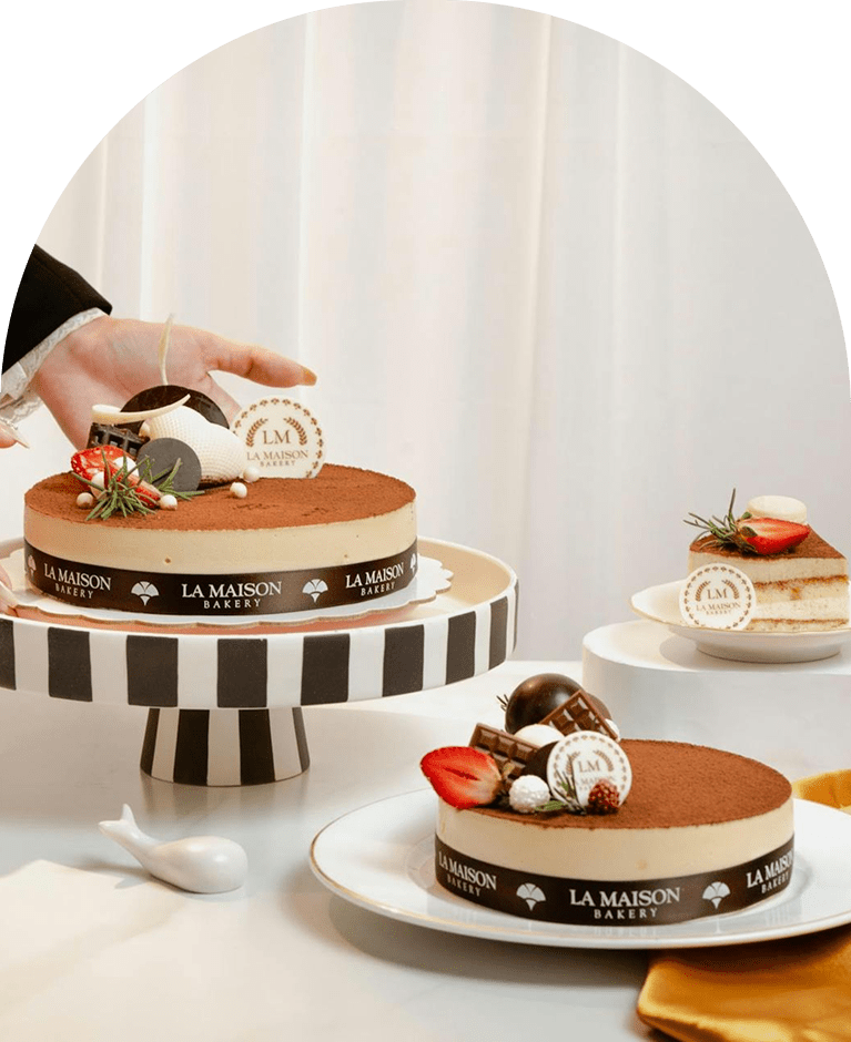 Pâtisseries tiramisu de La Maison Bakery avec cacao, fraises et chocolat décorées du logo LM