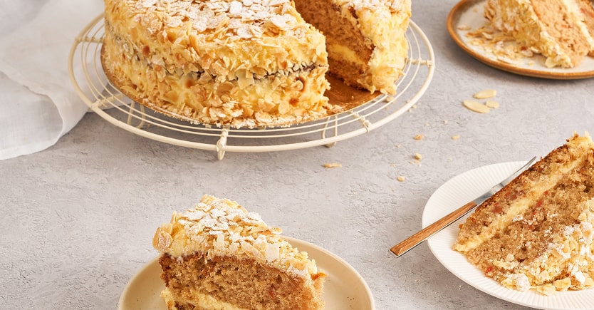 Gâteau aux amandes avec glaçage et flocons d'amandes, présenté sur un plateau et en parts individuelles