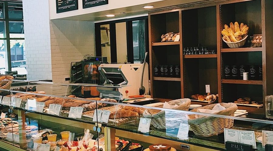 Intérieur d'une boulangerie avec vitrines de pains et pâtisseries, comptoir de service, étagères en bois et équipements