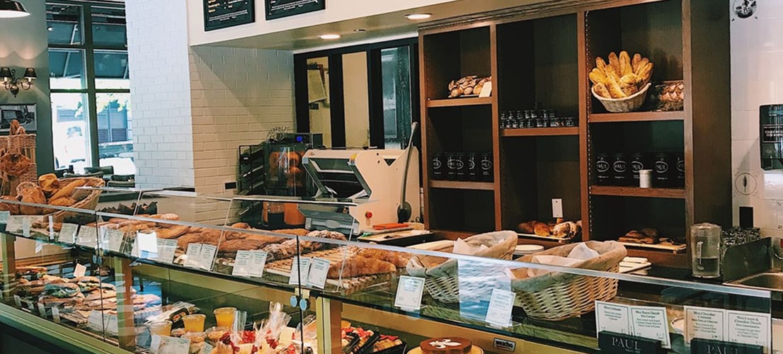 Intérieur d'une boulangerie avec vitrines de pains et pâtisseries, comptoir de service, étagères en bois et équipements