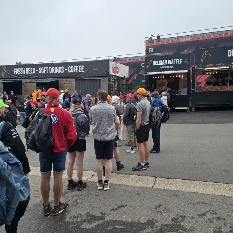 Foule de visiteurs devant des food trucks vendant bière, gaufres belges et café lors d'un événement en plein air