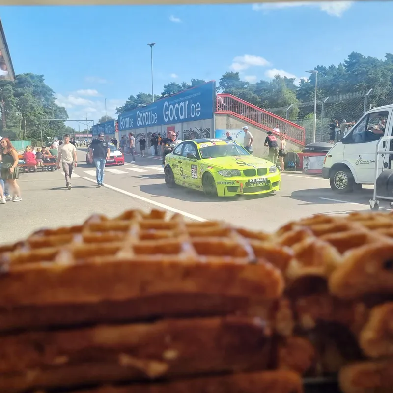 Stand Gocaribe avec voiture BMW jaune de taxi à un événement public, gaufres de Liège au premier plan