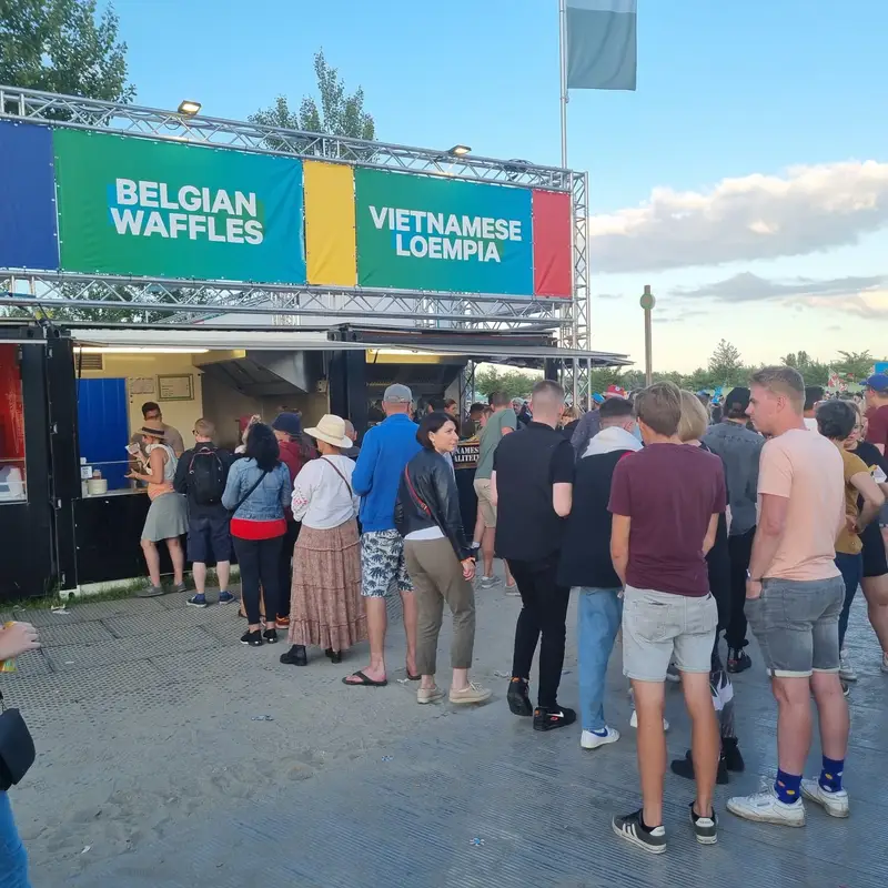 File d'attente devant un food truck avec enseigne Belgian Waffles et Vietnamese Loempia lors d'un événement festif