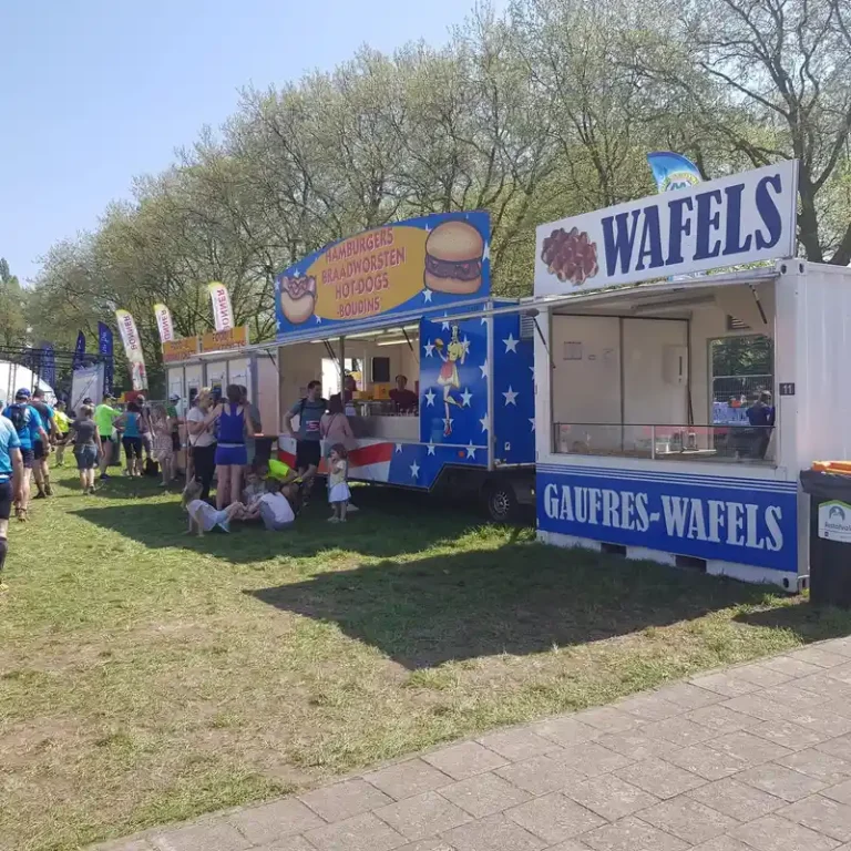 Food truck bleu et blanc Gaufres-Wafels avec signalisation de vente de gaufres et de hamburgers lors d'un événement en plein